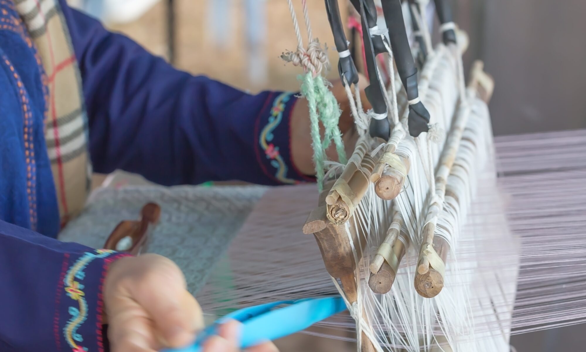 Midsection of a woman weaving textile in a loom
