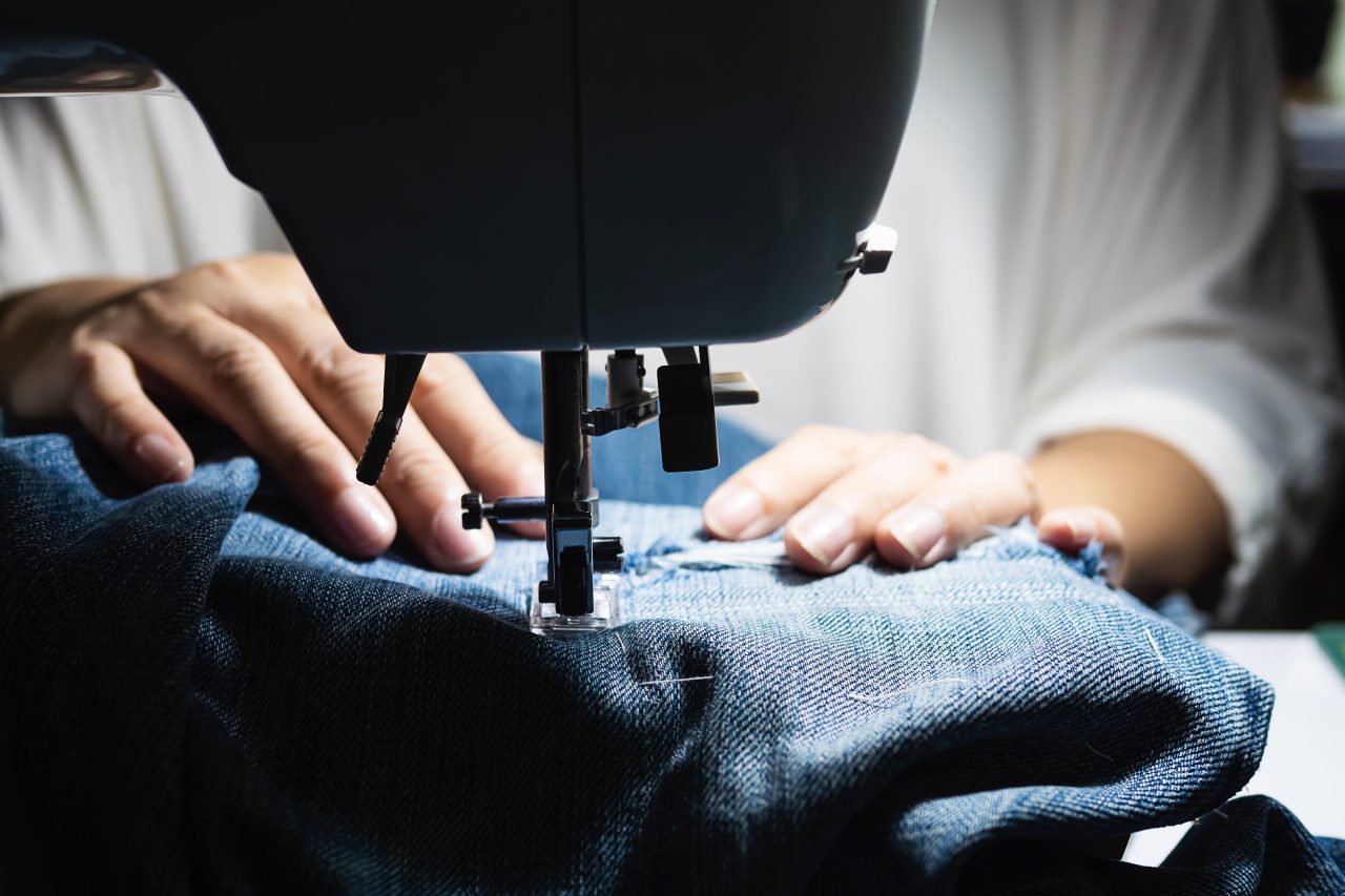 Stitcher sewing jeans on machine