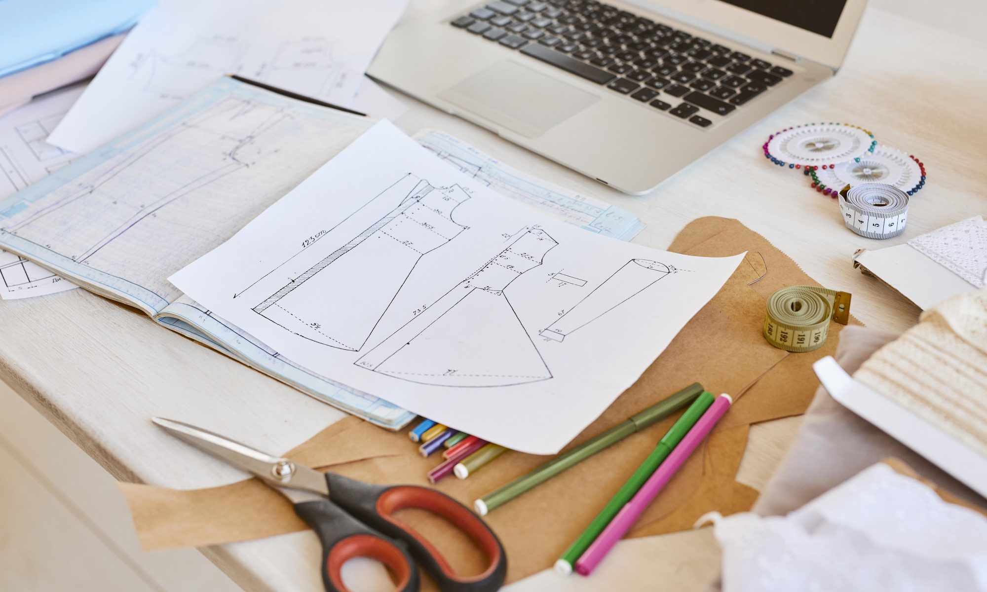 Paper tech pack sheets with a laptop and supplies